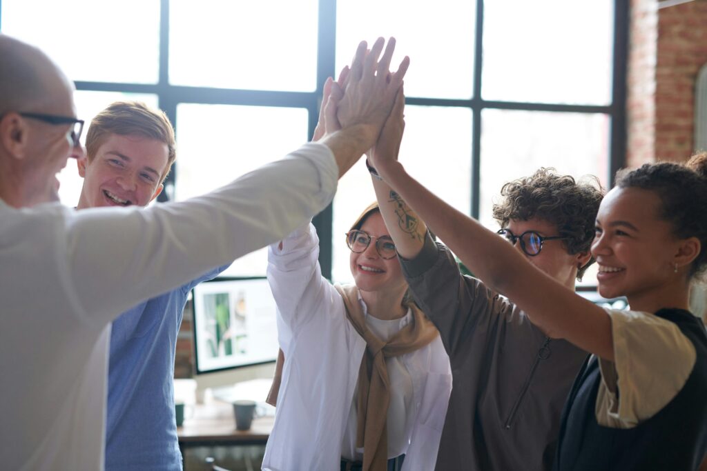 pexels-photo-3184427-3184427 A diverse team of professionals celebrating success with a high five in a modern office.